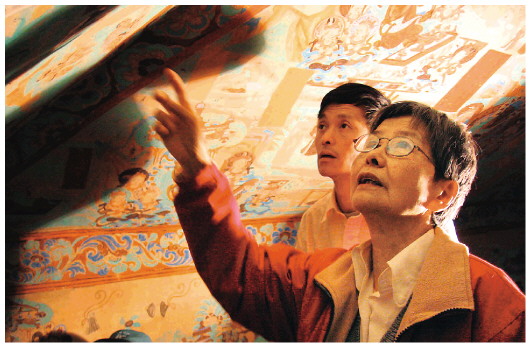 ▲樊錦詩（右一）在莫高窟第八十五窟壁畫修復(fù)現(xiàn)場。（敦煌研究院供圖）